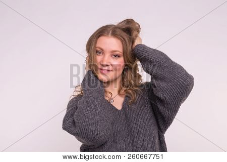 Portrait Of Fashionable Young Blonde Woman With Curly Hair In Grey Cardigan On White Background