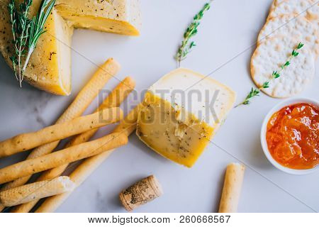 Cachotta Cheese With Herbs, Jam, Baguette, Crackers, Rosemary And Thyme On Marble