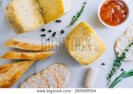 Cachotta Cheese With Herbs, Jam, Baguette, Crackers, Rosemary And Thyme On Marble