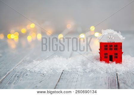 Wooden Toy House In A Snow And Light Boche On A Wooden Background