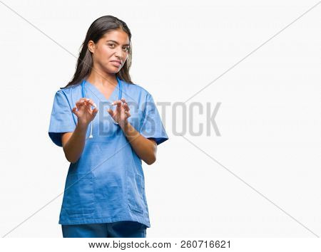 Young arab doctor surgeon woman over isolated background disgusted expression, displeased and fearful doing disgust face because aversion reaction. With hands raised. Annoying concept.