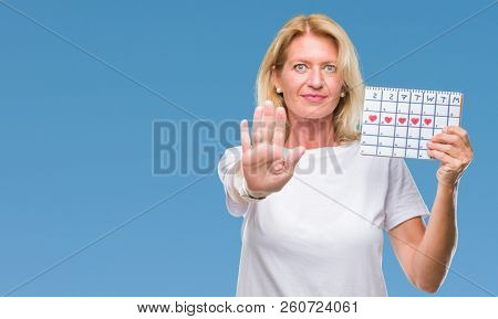 Middle age blonde woman holding menstruation calendar ver isolated background with open hand doing stop sign with serious and confident expression, defense gesture