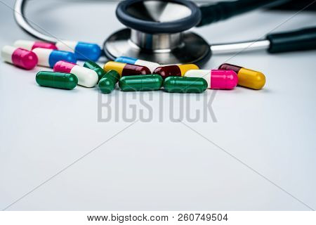 Green Stethoscope With Pile Of Antibiotic Capsule Pills On White Background. Antimicrobial Drug Resi