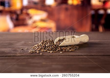 Lot Of Whole Fresh Brown Flaxseeds With Wooden Scoop With Rustic Wood Kitchen In Background