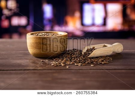 Lot Of Whole Fresh Brown Flaxseeds In A Scoop With Wooden Bowl With Restaurant In Background