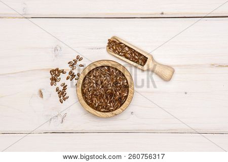 Lot Of Whole Fresh Brown Flaxseeds In A Scoop With Wooden Bowl Flatlay On White Wood
