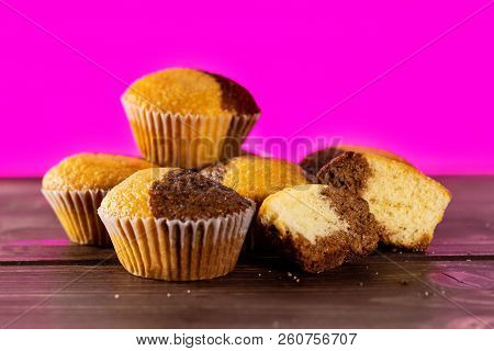 Group Of Four Whole Two Halves Of Fresh Baked Marble Muffin With Pink In Background