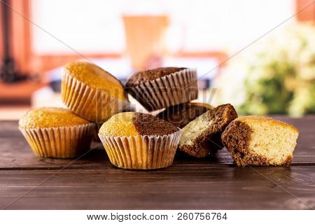 Group Of Five Whole Two Halves Of Fresh Baked Marble Muffin With Books Near The Window In Background
