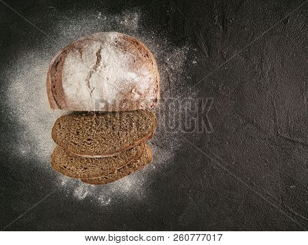 Sliced Homemade Sourdough Rye Bread With Rye Flour On Black Textured Background. Top View Or Flat-la