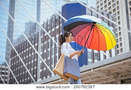 Asian Young Girl Smling And Holding Shopping Bags With Umbrella In City,lifestyle Concept