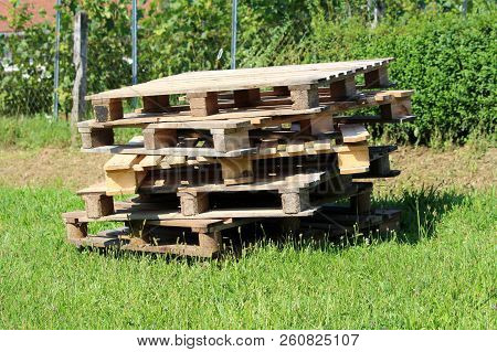 Multiple Wooden Pallets Left On Small Pile In Backyard For Later Use Surrounded With Uncut Grass And