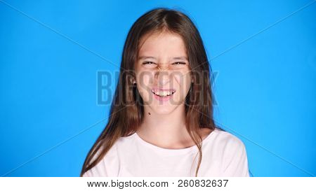 Cute The Girl Teenager Looks Into The Camera Laughing And Makes A Funny Facial Expression. Close-up.