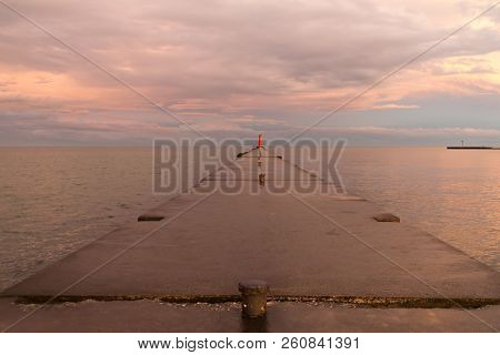 A Lighthouse Pier On Lake Michigan At Sunset With Pink Clouds Reflected In The Water.  Sheboygan, Wi