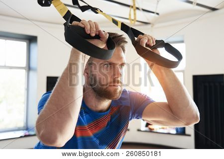 Portrait Of Handsome Man Athlete Doing Exercise Alone With Fitness Belts In Modern Gym Club, Workout