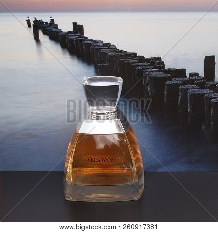 Vera Wang, Fragrance For Ladies, Large Perfume Bottle In Front Of The Picture Of A Groyne In The Sea