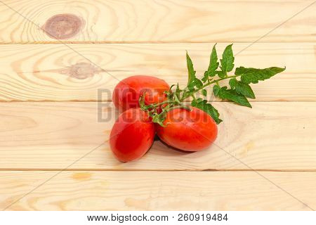 Branch Of The Red Plum Tomatoes With Water Drops And Leaf Of Tomato Plant On A Light Colored Wooden 
