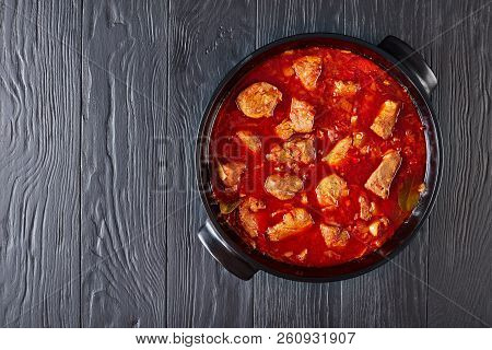 Hot Red Chile And Pork Stew Or Carne Adobada In A Dutch Oven On A Black Wooden Table, Mexican Cuisin