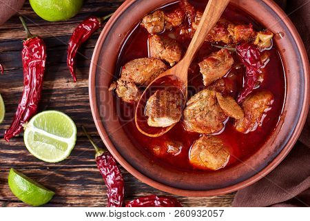 Carne Adobada Or Hearty Red Chile And Pork Stew In A Clay Bowl With Spoon On An Old Wooden Table Wit