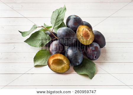 Fresh Plum Fruit With Leaves On A Light Table.