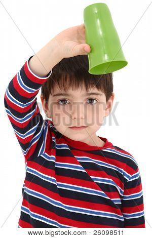 Niño que sostiene la taza vacía boca abajo con la expresión decepcionado.