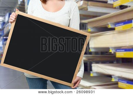 Young woman holding blank blackboard at a hardware store.