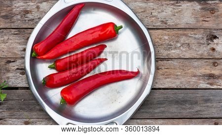 Red Hot Peppers Lie On A Steel Vintage Plate On Wooden Old Boards Background. View From Above. Space