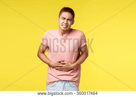 Health, People And Food Concept. Asian Guy In Pink T-shirt, Feel Sick, Grimacing From Pain In Stomac