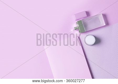 Flat Lay Female Workplace. Notebook, Perfume And Cream On A Nion Pink Background. The Design Of The 