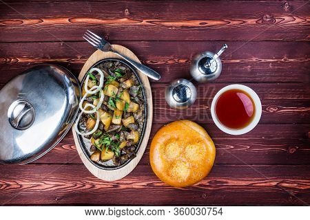 Kuurdak - Traditional Meat Dish Made In Central Asia. Serving On A Hot Frying Pan With A Pepper Grin