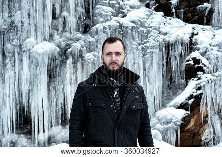 Man standing against cliff full of icicles