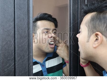 A Man Looking At His Reflection In Mirror Nose Picking And Checking His Nasal Cavity For Nose Infect