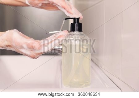 Man Cleaning His Hands Using Liquid Disinfectant Soap And Water In Bathroom.