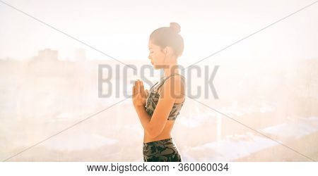 Yoga at home meditation exercise for mental health wellness well-being during self isolation quarantine of COVID-19 Coronavirus outbreak pandemic. Asian fit girl meditating .