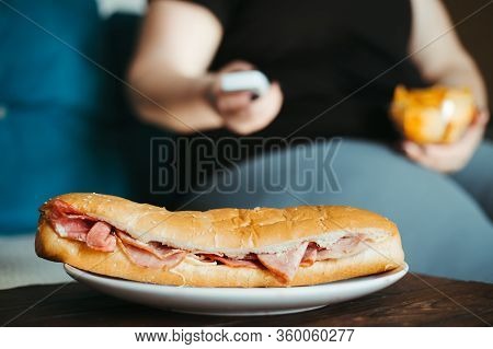 Mindless Snacking, Home Sedentary Lifestyle, Compulsive Overeating. Obese Lazy Woman Sitting On Sofa