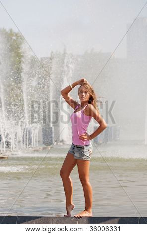 meisje in een roze vest en broek kosten aan een kant van de fontein