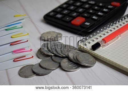 Calculator And The Stack Of Coint Isolated On Office Desk. Calculating Salary Or Tax Concept