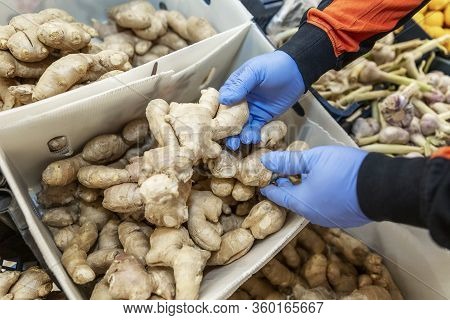 Hands In Blue Medical Gloves Pick Ginger On A Counter In A Store. Medication During The Coronavirus 
