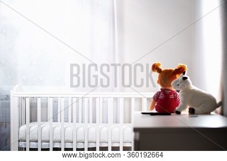 Childrens White Room With An Empty Cradle And Toys On The Dresser. Copy Space. Horizontal. The Conce