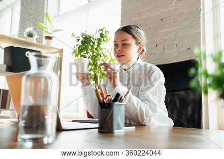 Drinking Coffee. Woman Working In Office Alone During Coronavirus Or Covid-19 Quarantine, Wearing Fa