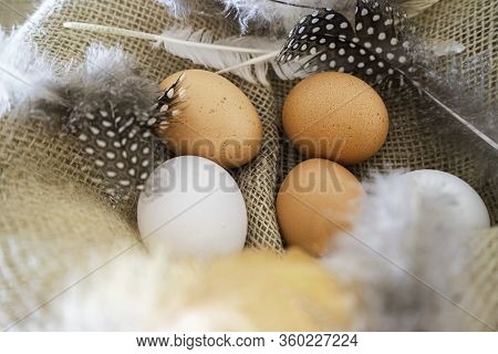 Different Coloured Eggs With Feathers Lying On A Jute Bag
