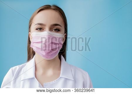 Doctor Nurse Smiling Behind Surgeon Mask. Closeup Portrait Of Young Caucasian Woman Model On Blue Ba