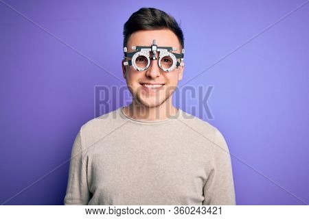 Young handsome caucasian man wearing optometrical glasses over purple background with a happy and cool smile on face. Lucky person.