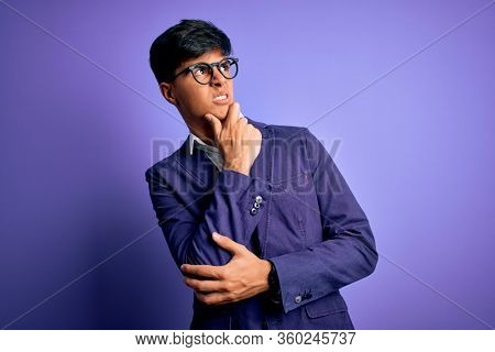 Young handsome business man wearing jacket and glasses over isolated purple background Thinking worried about a question, concerned and nervous with hand on chin