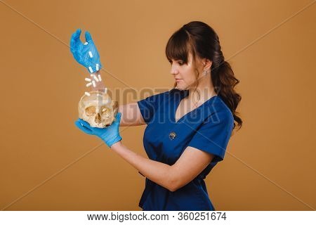 Pretty Young Concentrated Trainee Girl Spills Pills Into A Skull From A Hand Dressed In Disposable G