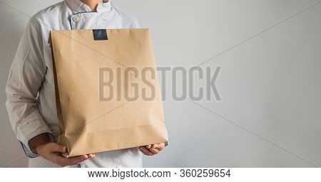 Chef Making A Delivery Of Food Takeaway In A Paper Carton Bag With Copy Space.