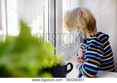 Sed Little Boy Looking Into Window During Coronavirus Pandemic. Child Boring Without Communication A