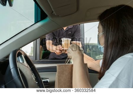 Woman In Protective Mask Taking Coffee At Drive Thru During Coronavirus Outbreak