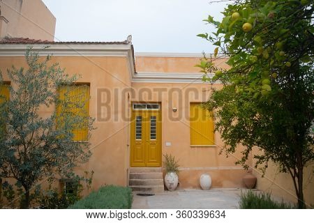Salmon Colored House Facade And Yellow Doors And Windows With An Olive And Lemon Tree In The Front Y