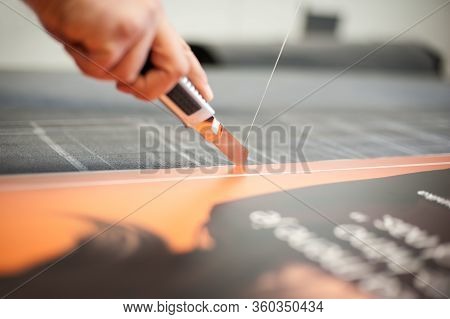 Close-up Of Hand With Skalpel. Worker Cut Paper In Printshop