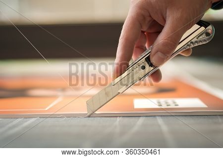 Close-up Of Hand With Skalpel. Worker Cut Paper In Printshop